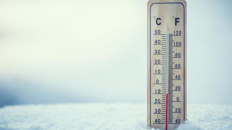 Thermometer on snow shows low temperatures under zero. Low temperatures in degrees Celsius and fahrenheit. Cold winter weather ten under zero.