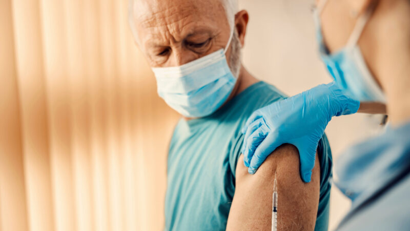 A senior man getting covid 19 vaccine in hospital. Vaccination, inoculation and health care.