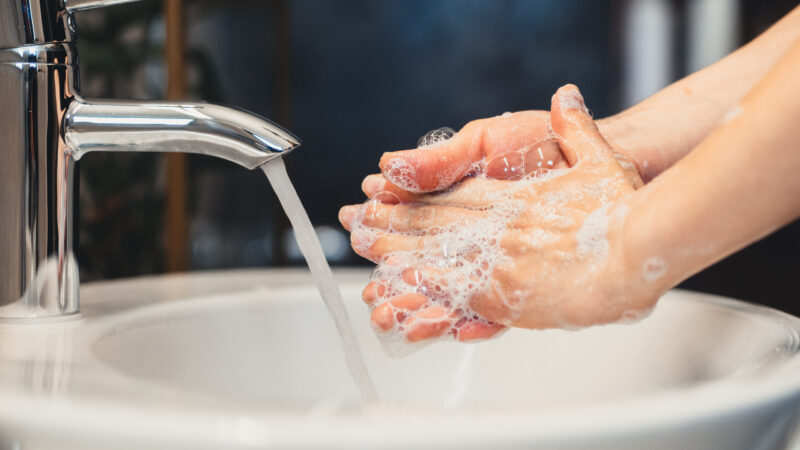 caucasian young woman carefully washing hands with soap and sanitiser in home bathroom